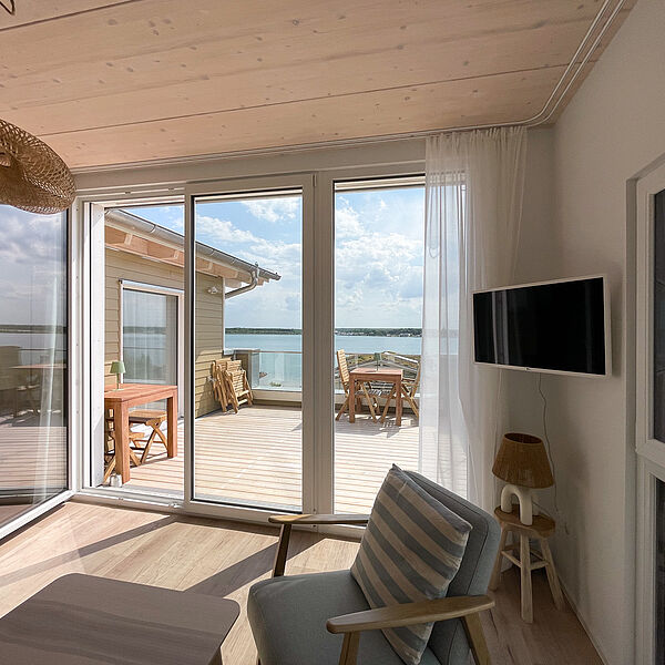 Dachterrasse mit zwei Holz-Tischen und Stühlen. Blick vom Wohn-Zimmer aus.