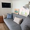 Graus Sofa mit Kissen, einem Smart TV und einer Stehlampe.
